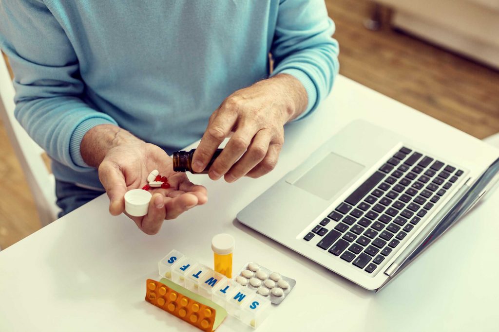 Senior pouring prescription pills on hand